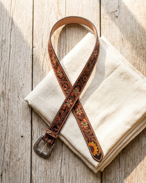 Decorative leather belt with floral patterns on a white fabric background